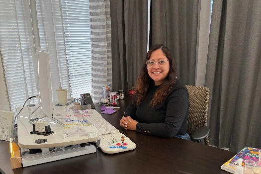 Nalleli Garrido, PMHNP-BC, smiling at her desk at the Solandis Mental Health clinic in Garden Grove.